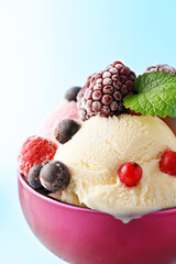 Ice cream with frozen fruit in a purple bowl. Red fruit. Blue background