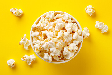 Popcorn viewed from above on yellow background. Flat lay of pop corn bowl. Top view - obrazy, fototapety, plakaty