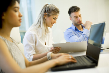 Young business people using laptop and smiling while working in office