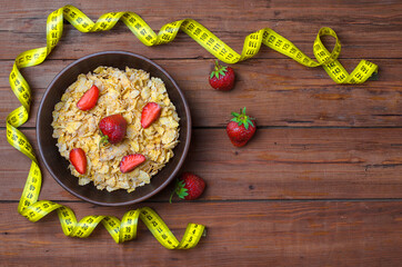 Dietary food: corn flakes and strawberries on a wooden table top view.