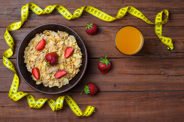 Dietary food: corn flakes and strawberries on a wooden table top view.