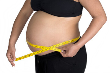 A pregnant woman uses a piece of measuring tape to take up the measurements of her pregnancy bump.