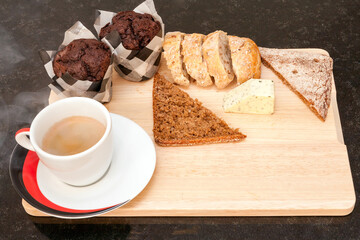 A cup of coffee with cutting bread and mafins. 