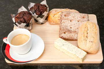 A cup of coffee with bread and mafins. 