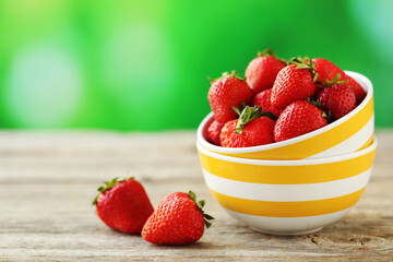Fresh and tasty strawberries in bowl on a grey wooden table