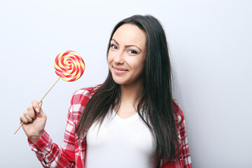 Young woman with lollipop on grey background