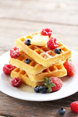 Homemade waffles with berries in plate on grey wooden table