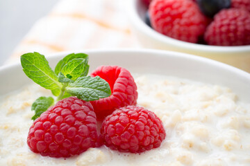 Oatmeal porridge in bowl with berries raspberries and blackberries.