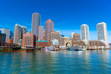 Fototapeta na wymiar Boston cityscape reflected in water, skyscrapers and office buildings in downtown against the clear blue sky, view from Boston harbor, USA