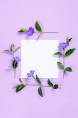 Square flower frame with white sheet on violet background.
