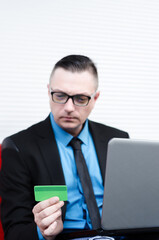 smart grown man in a suit sitting with a laptop and purchases over the Internet with a credit card