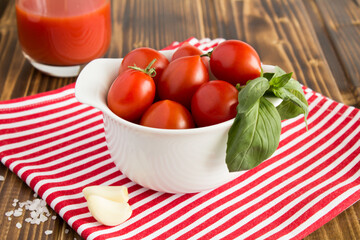 Red tomatoes with tomato juice, garlic and salt on a wooden table