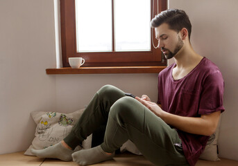 Fototapeta premium Happy man using mobile phone at home