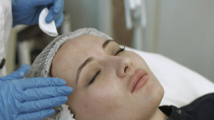 Fototapeta na wymiar Cosmetologist applies cream on the skin of the client