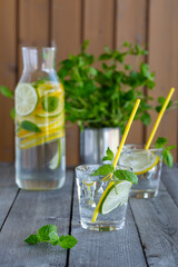 Water with lime and mint in glasses on a old wooden table