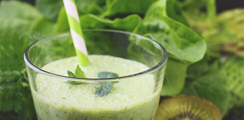 Green smoothies with spinach, cucumber and parsley in a glass on a black background