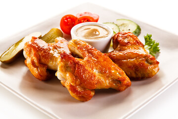 Grilled chicken wings with vegetables on white background