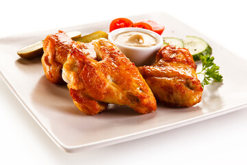 Grilled chicken wings with vegetables on white background