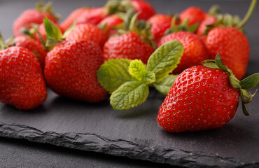 Ripe strawberries with a mint leaf on a black background