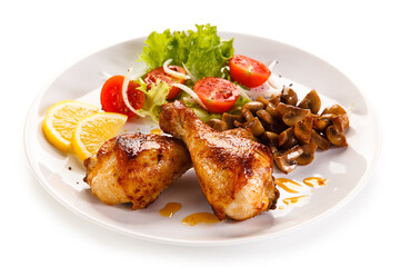 Grilled chicken drumsticks with vegetables on white background