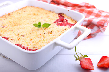 crumble with strawberries in white plate on a white background