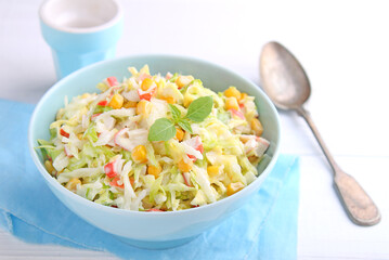Salad of young cabbage with corn and crab sticks in blue bowl