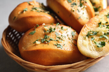 Tasty bread with garlic, cheese and herbs in wicker basket