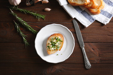 Tasty bread slice with garlic and herbs on plate