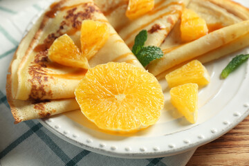 Tasty pancakes with orange slices on plate