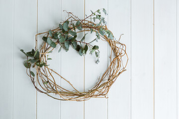Eucalyptus and ivy wreath on white wooden background