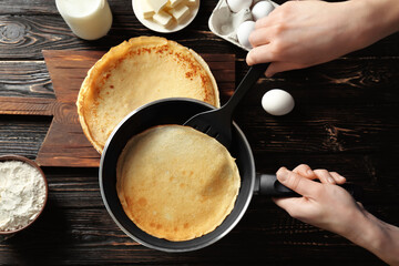 Woman cooking Russian pancakes in kitchen, closeup © Africa Studio