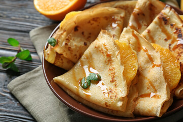 Tasty pancakes with orange slices on plate