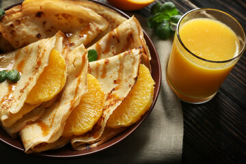 Tasty pancakes with orange slices on plate