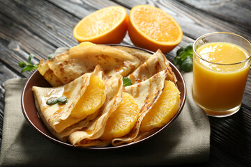 Tasty pancakes with orange slices on plate