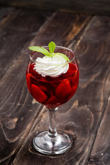 Strawberry jelly, strawberry and ice cream with mint in a glass on a wooden table, country style