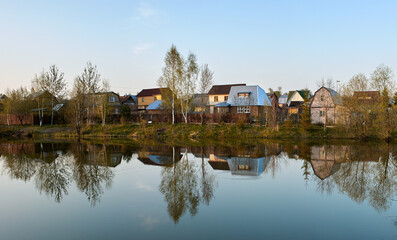 Fototapeta na wymiar Panorama of village houses in a reflection of the lake at sunset