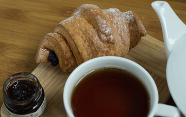 Delicious fresh croissants with fruit jam and tea on wooden
