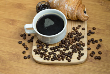 Delicious fresh croissants with fruit jam and coffee on wooden