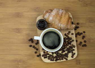 Delicious fresh croissants with fruit jam and coffee on wooden