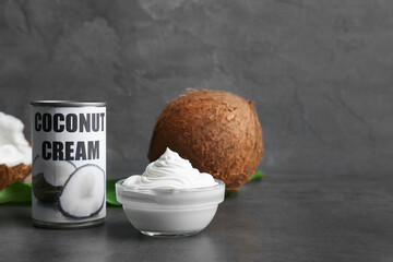Coconut cream in bowl and tin on dark background