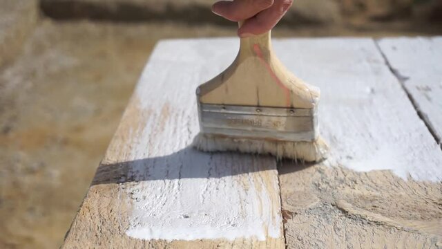 Close-up video of girl's hand with a brush painting wooden table