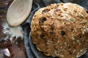 Freshly baked bread with dried tomatoes and garlic, wooden spoon and flour