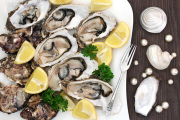 Oyster shellfish on a porcelain plate with lemon fruit, parsley herb, antique silver fork, pearls...