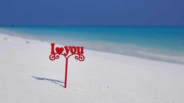 Sign I love you on Maldivian beach with white sand and turquoise sea water. Honeymoon on Maldive island