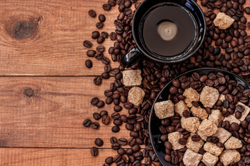 a Cup of coffee, cane sugar and coffee beans on wooden table