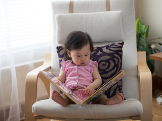 baby girl reading book at home