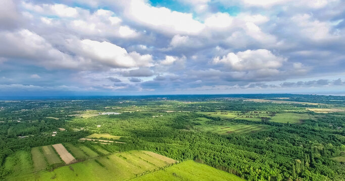view from the quadrocopter to the fields and forests under the clouds