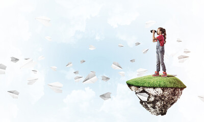 Obraz premium Concept of careless happy childhood with girl looking in binocul