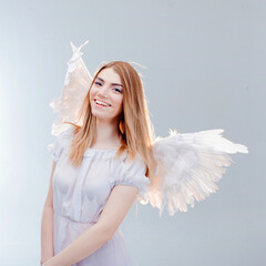 An angel from heaven. Young, wonderful blonde girl in the image of an angel with white wings.