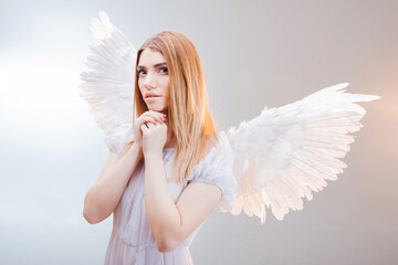 An angel from heaven. Young, wonderful blonde girl in the image of an angel with white wings.